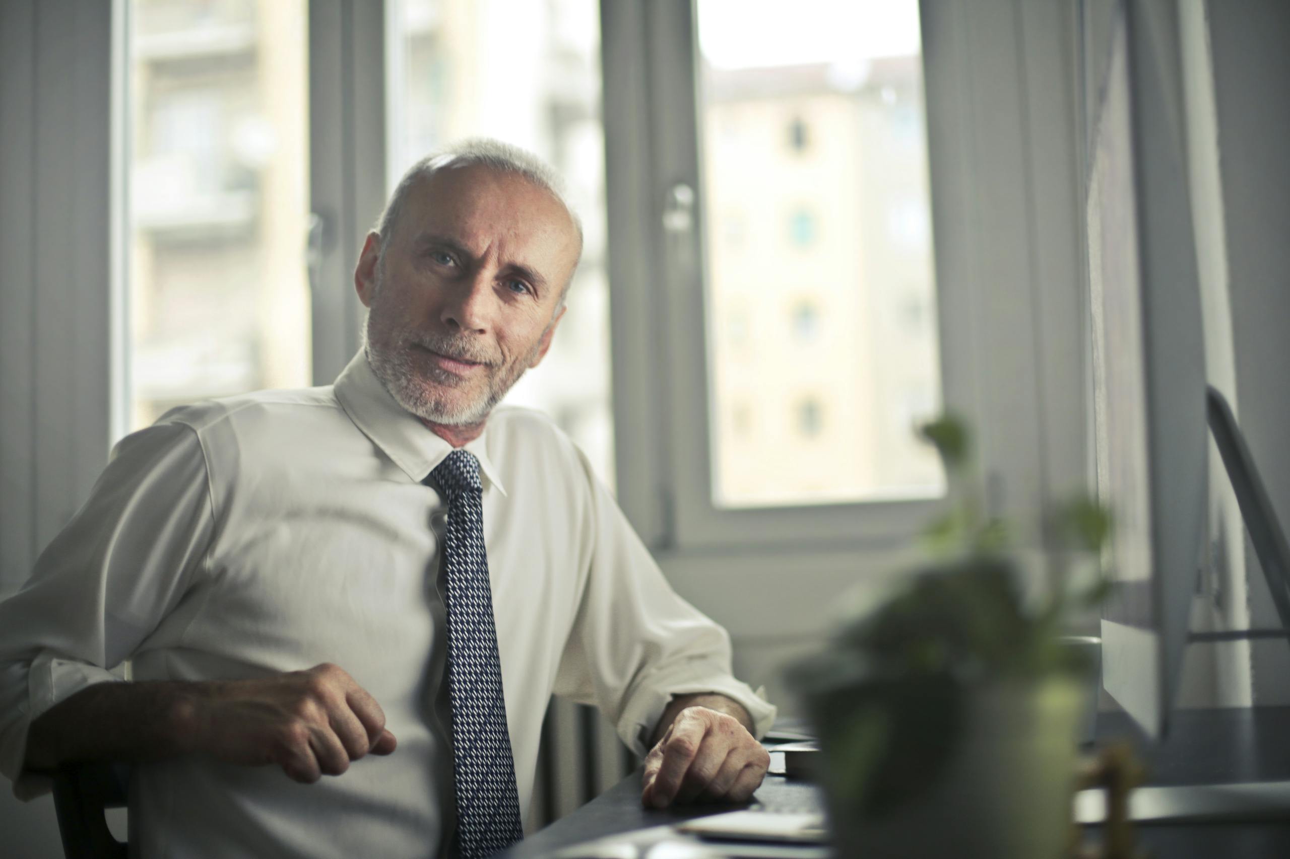 Henkilö A mature man in professional attire smiling in an office setting.